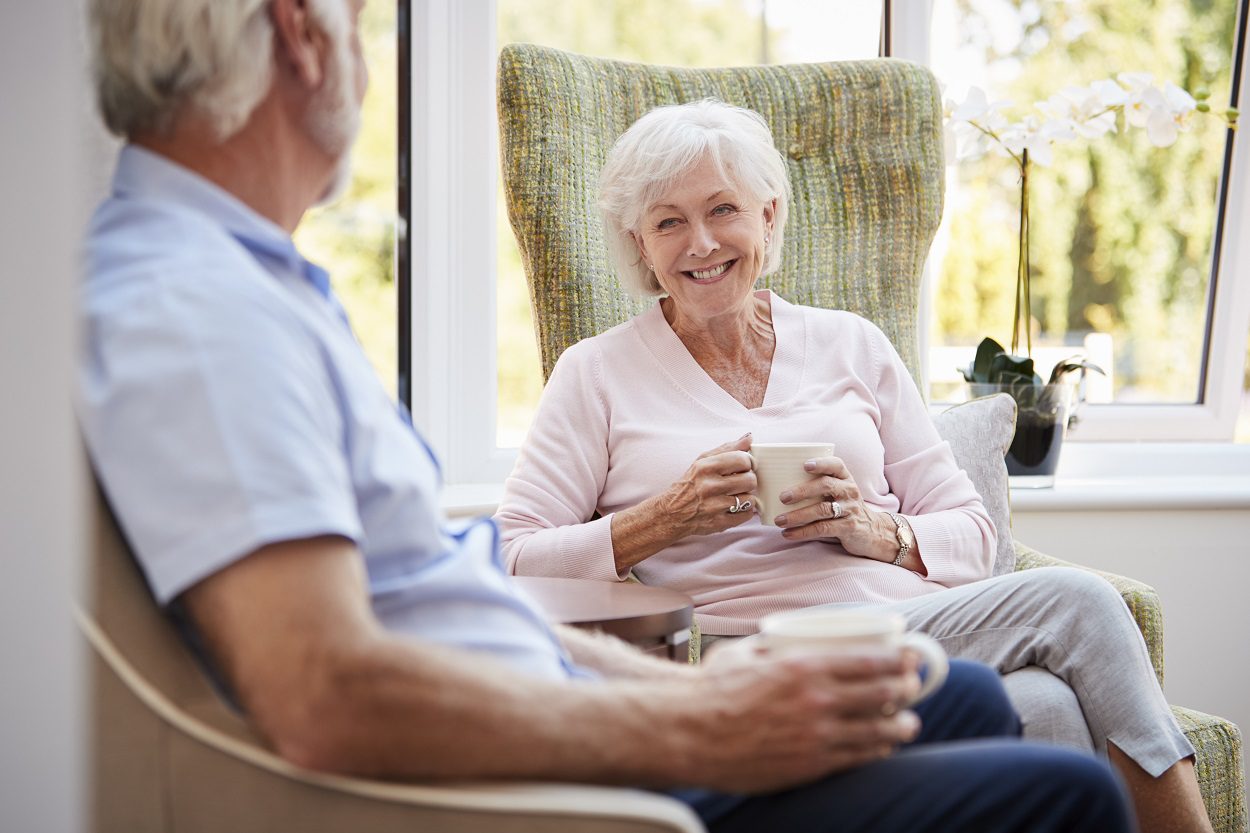 Senior couple sitting and chatting at retirement home