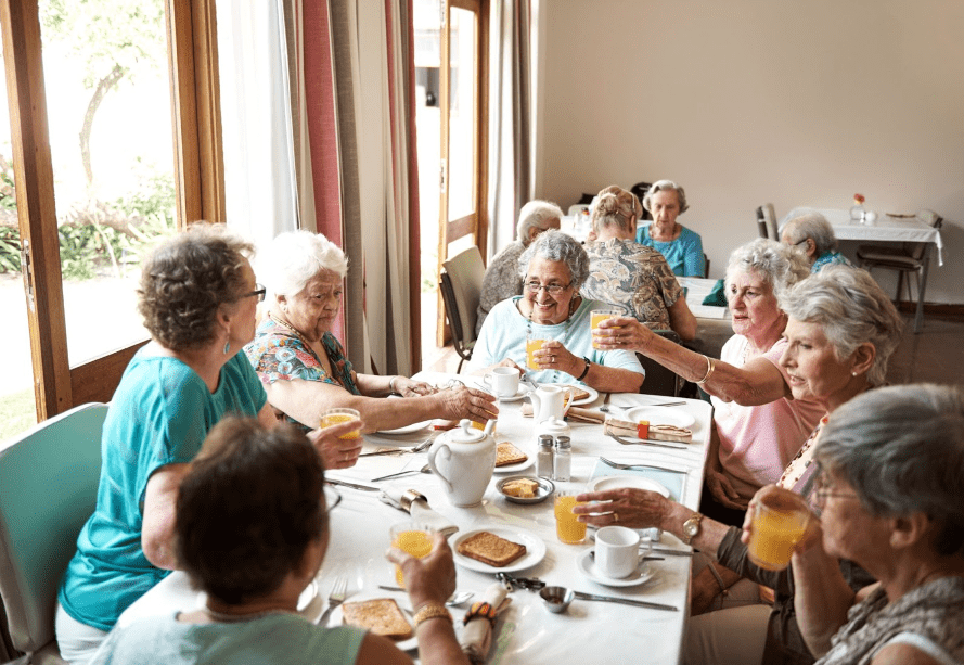 A group of seniors sharing a meal and enjoying each other's company in a retirement community dining room.