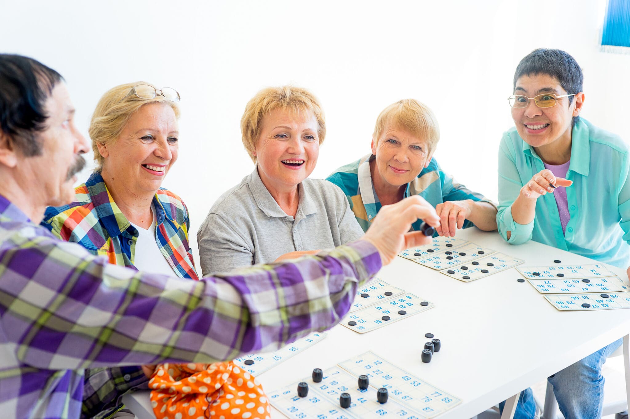 A group of seniors sitting around a table, joyfully playing a game together.