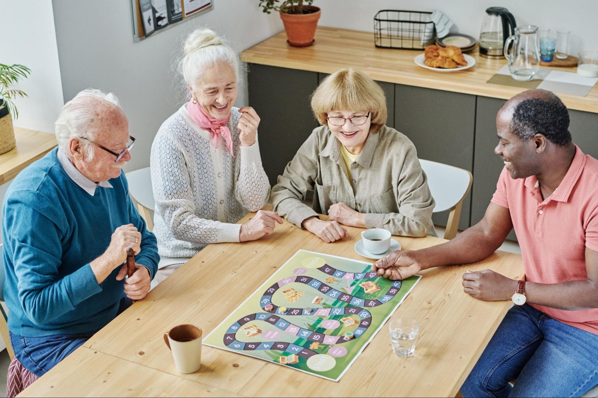 A diverse group of seniors gathered around a wooden table, laughing and playing a colorful board game together in a cozy, home-like setting, promoting cognitive engagement and social interaction.