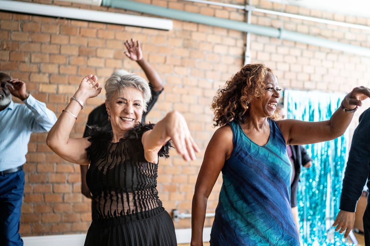 Older adults smiling and having fun as they participate in a dance class in a vibrant retirement residence.