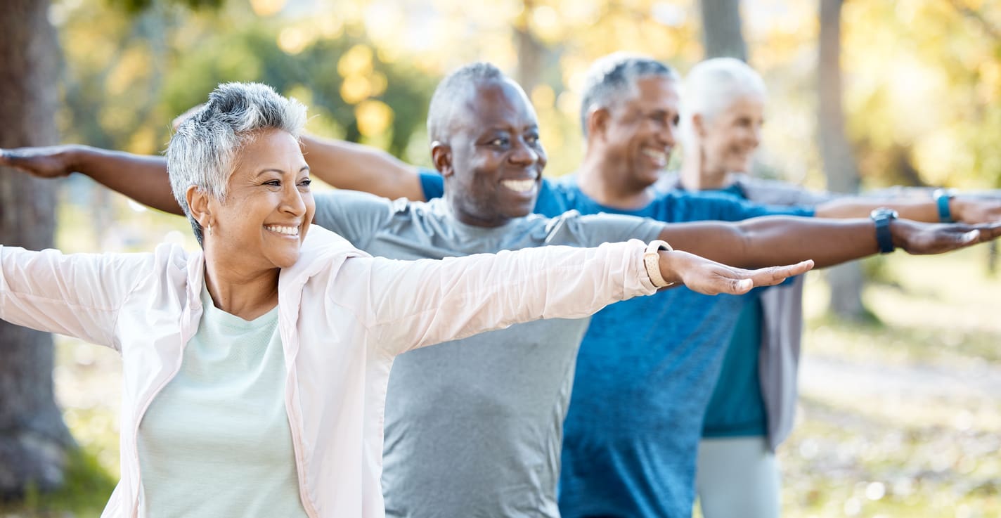 Seniors enjoying a group yoga session outdoors at a retirement community, promoting physical and mental wellness.