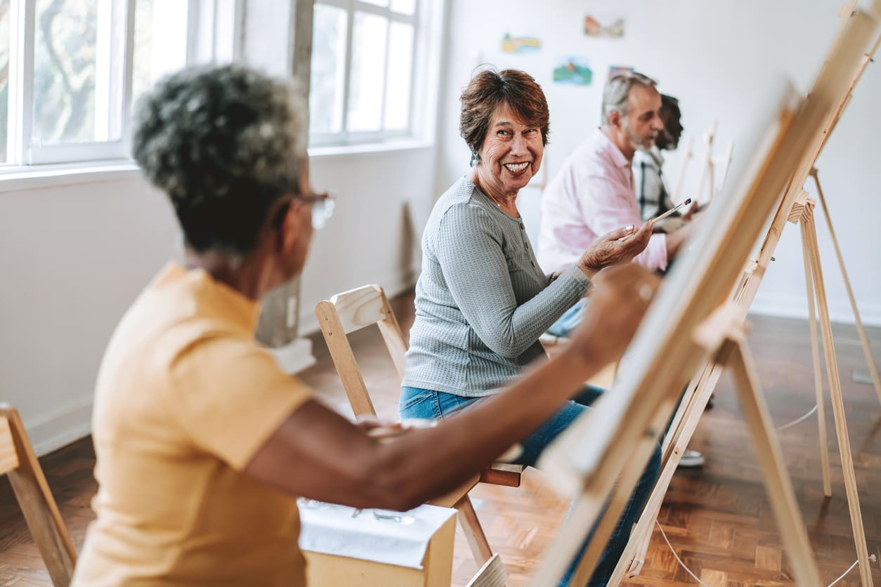 Older adults participating in a cheerful art class, showcasing retirement living in a creative and engaging environment.