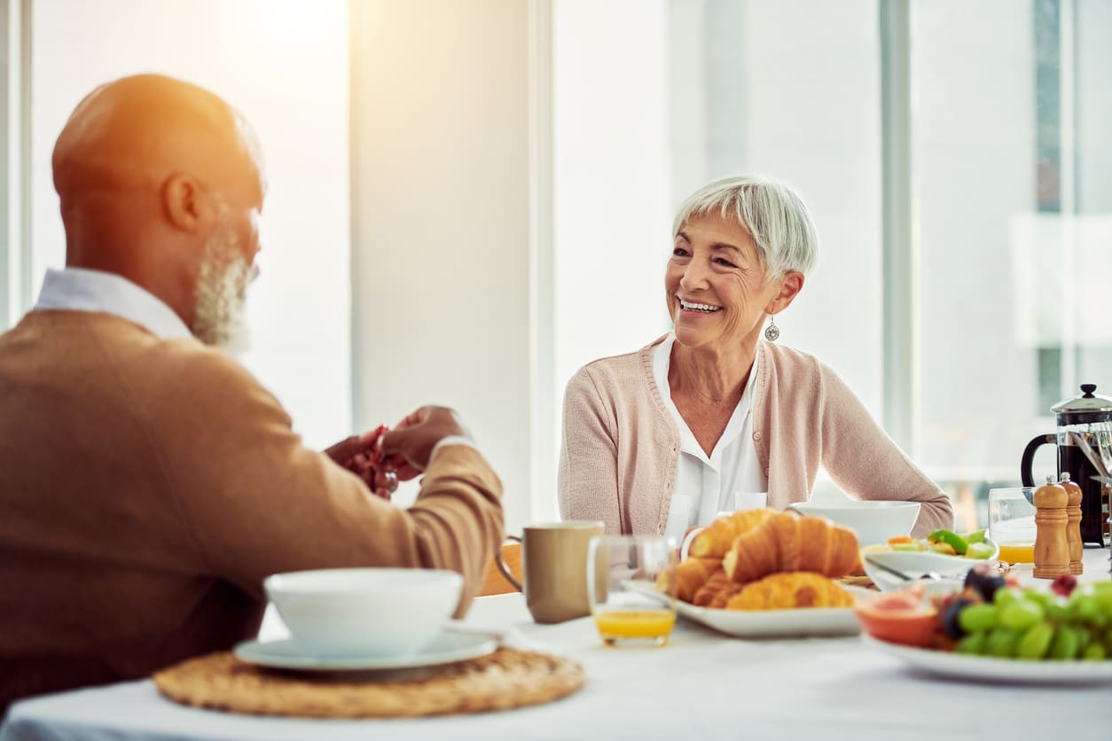 Older adults enjoying a healthy lunch and friendly conversation in a bright retirement residence dining room.