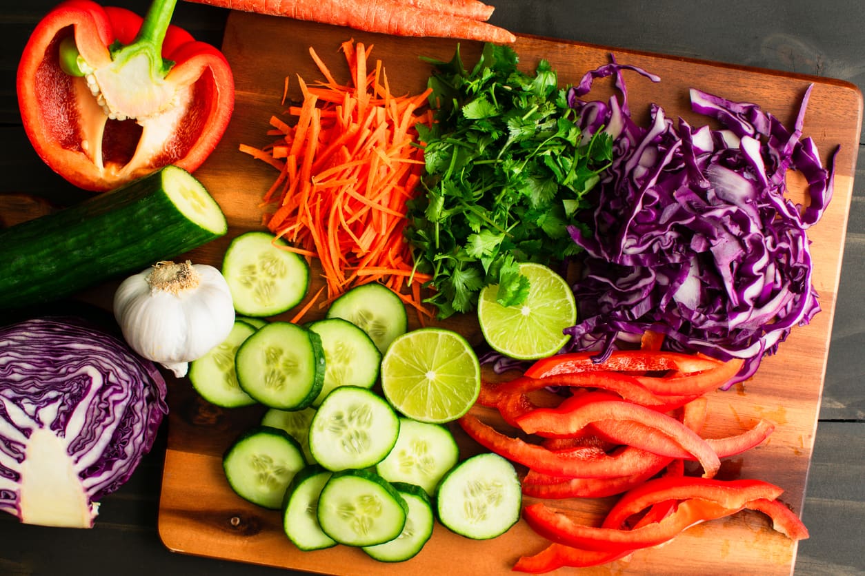 Freshly chopped vegetables and herbs on a cutting board in a retirement community kitchen.