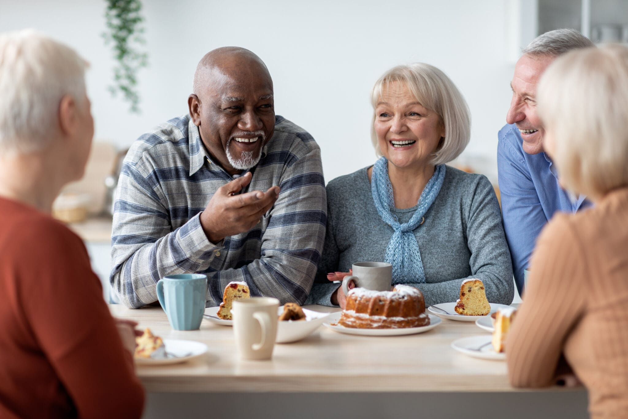 Residents socializing over coffee and dessert in a retirement community dining space.